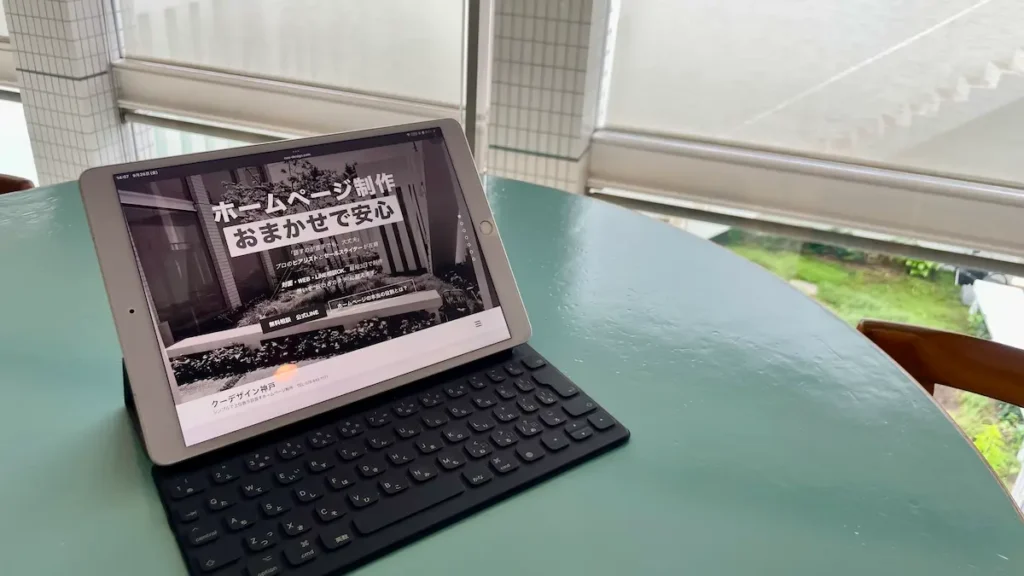 事務所のテーブルでタブレットとキーボードを使い、cuu design神戸の公式サイトを確認している様子